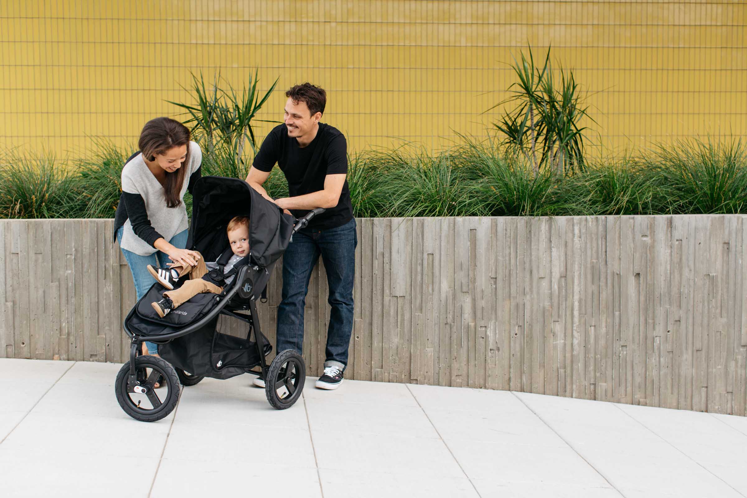 Black Bumbleride Indie Stroller with parents, child, Toshi baby romper, Odyssey wagon wheels