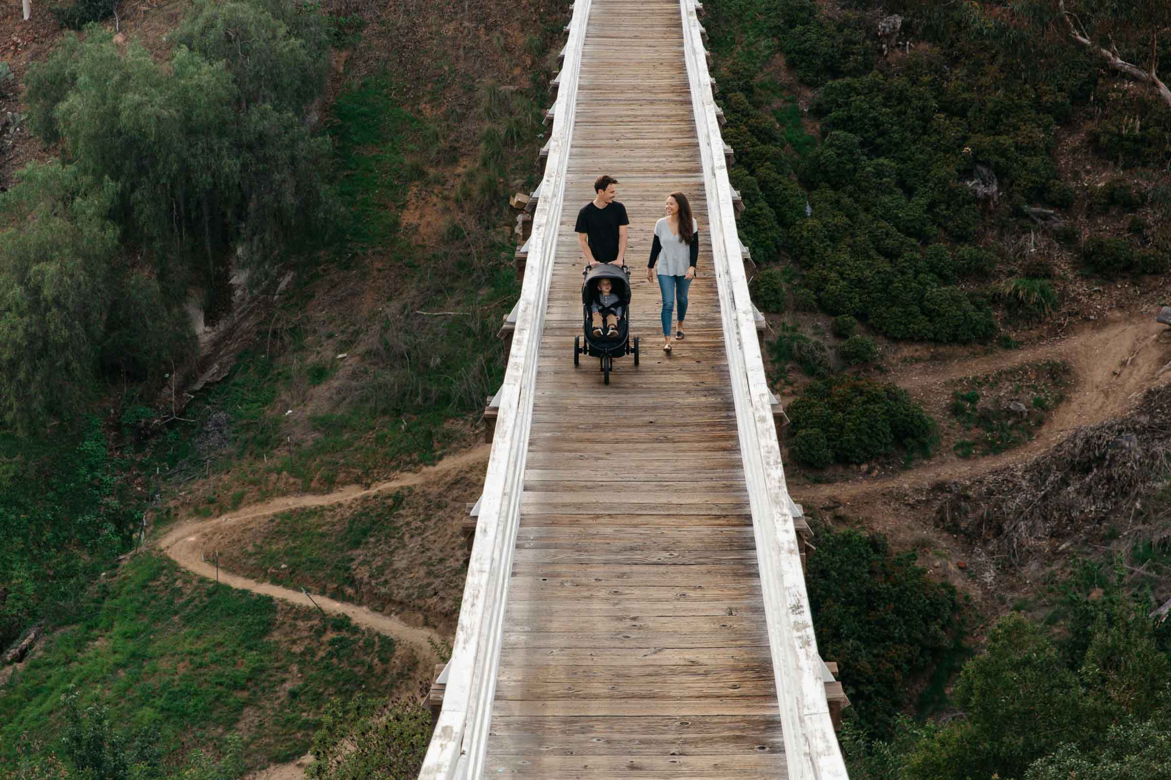 Family walking on a wooden bridge with a Bumbleride Indie Stroller and Odyssey wagon wheels