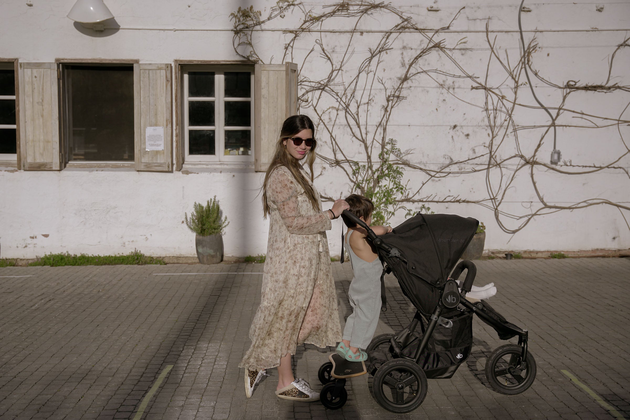 Black Bumbleride Indie Stroller with child, styled with Toshi Baby Romper and Odyssey Wagon Wheels