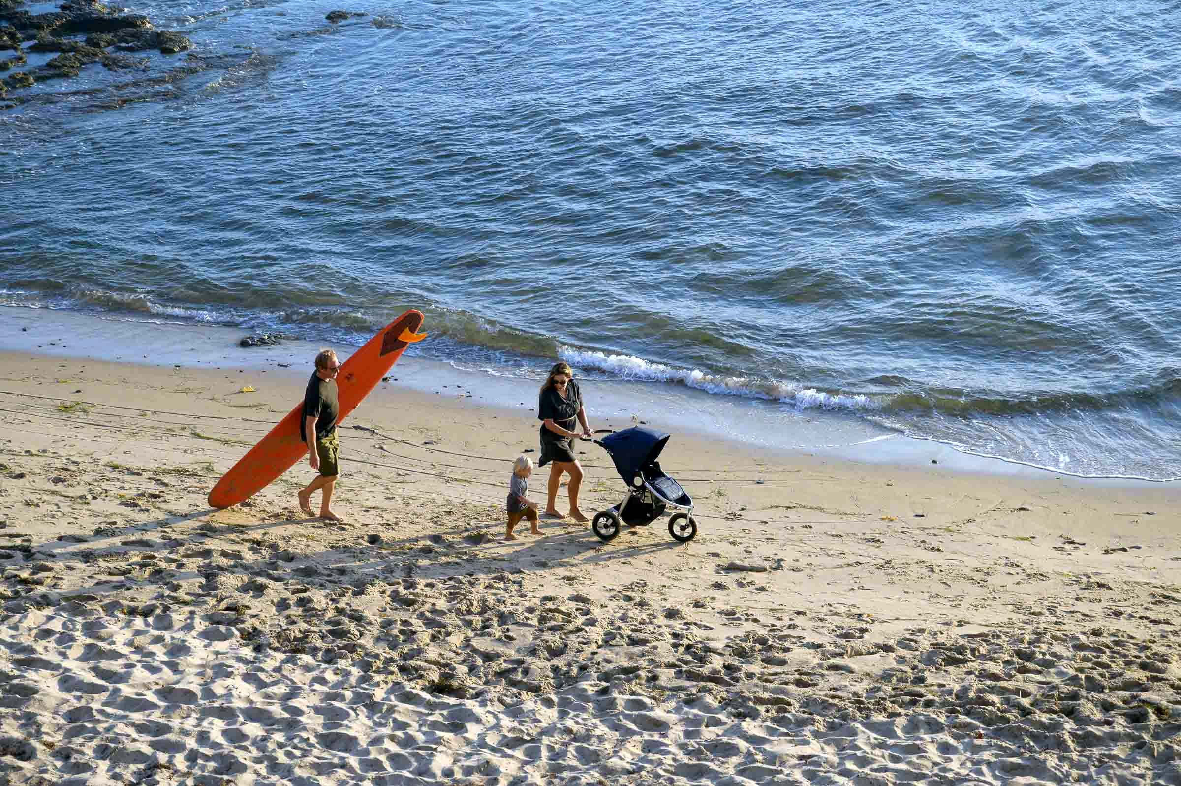 Family walking on beach with Bumbleride Indie Stroller and Toshi Baby Romper