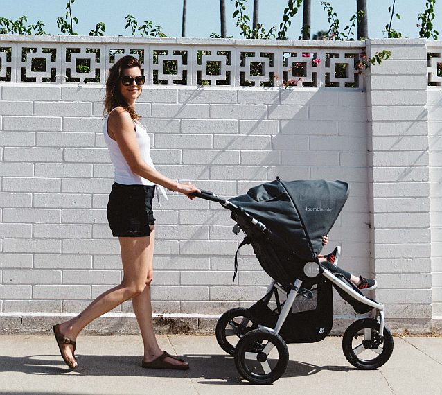 Woman pushing a Bumbleride Indie Stroller with Toshi Baby Romper and Odyssey Wagon Wheels