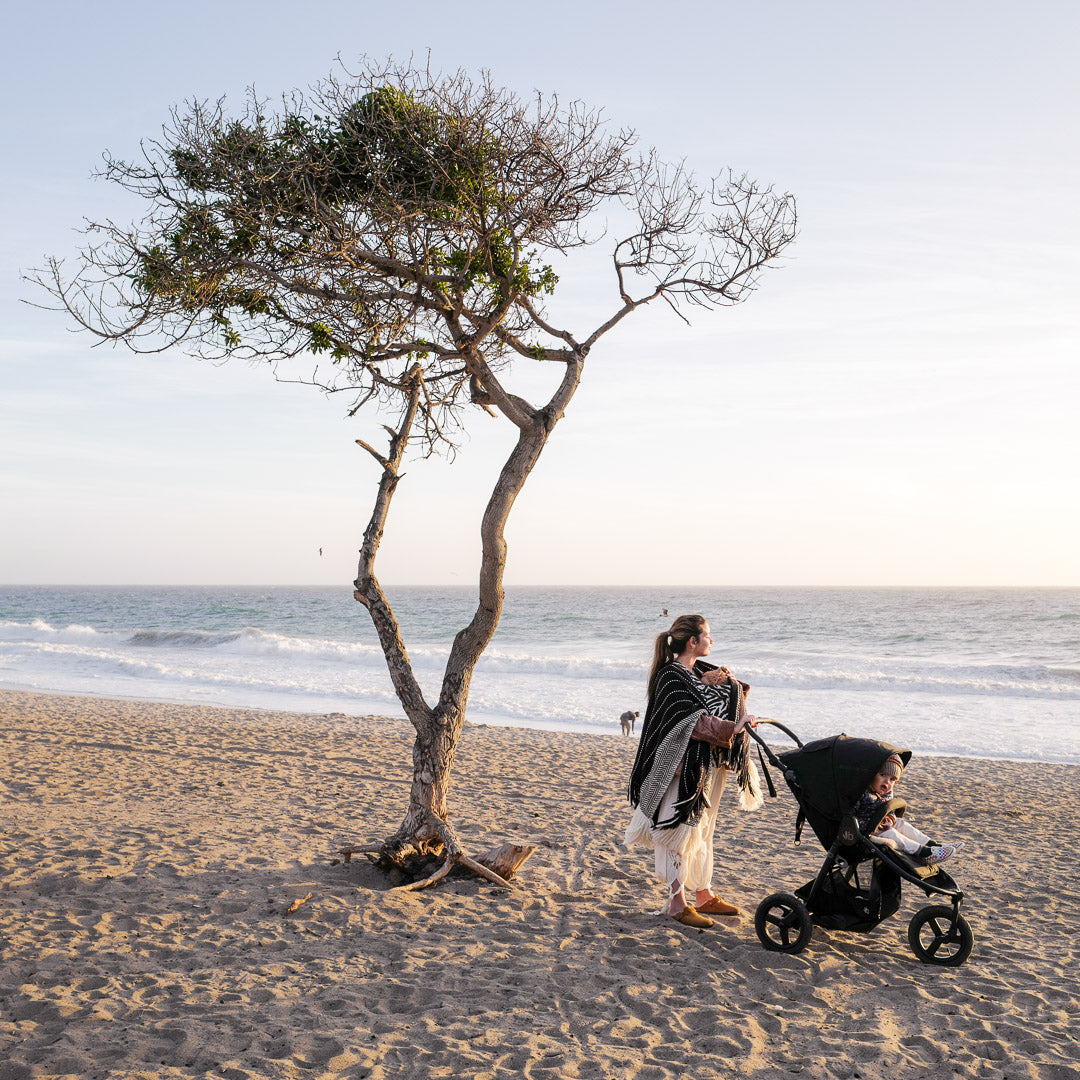 Beachside stroller scene featuring Bumbleride Indie Stroller and Toshi baby romper