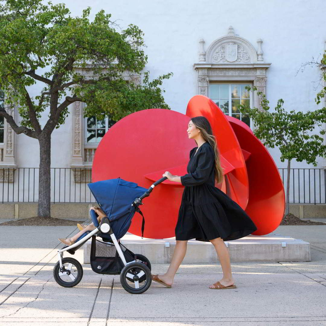 Woman pushing a blue Bumbleride Indie Stroller with a Toshi Baby Romper for baby strollers