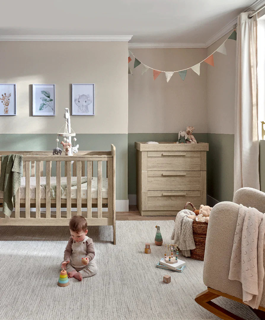 Nursery with baby playing on fitted sheets in Mamas&Papas Atlas 5 Piece Set Light Oak