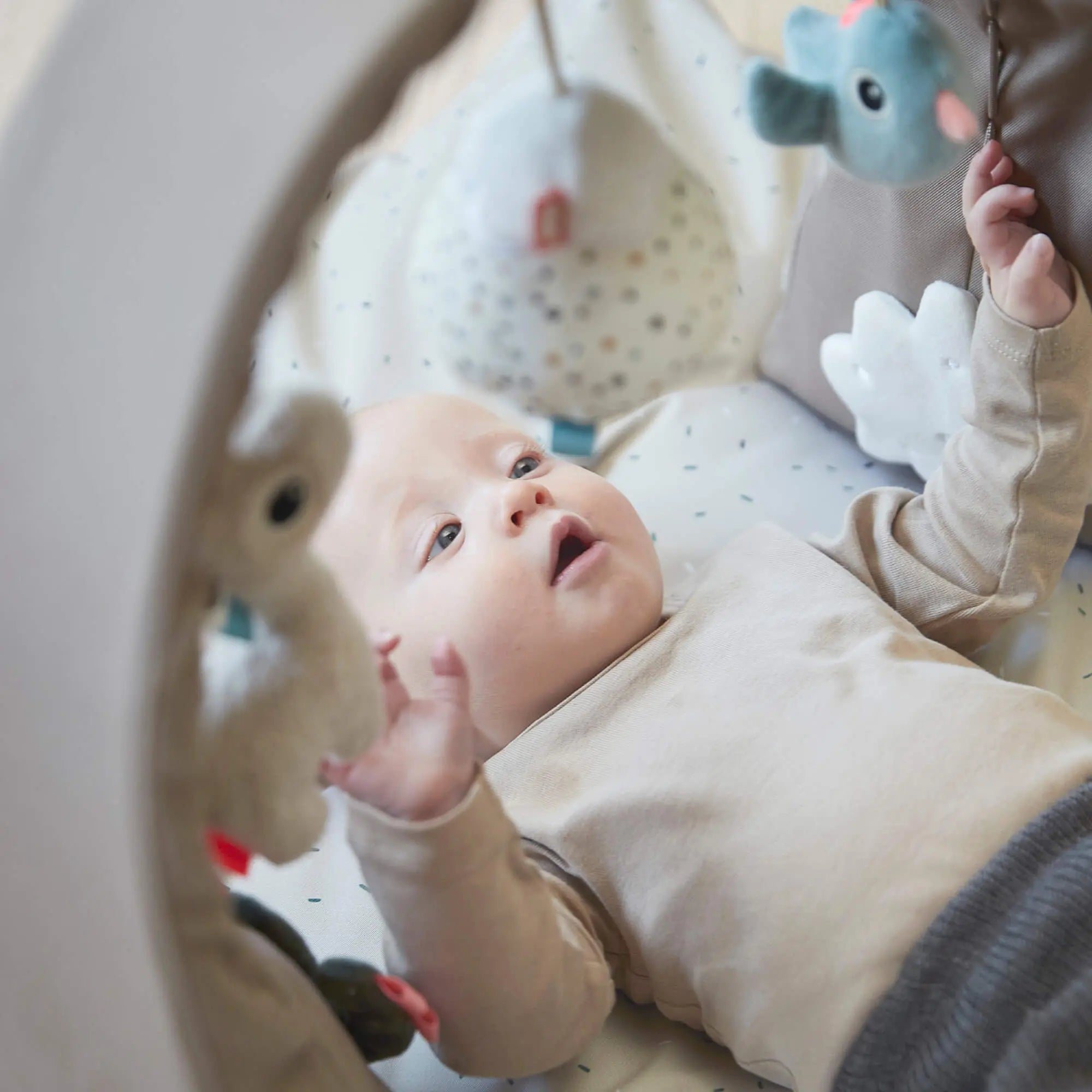 Baby in a play gym featuring a discovery textile patch in the Done by Deer Activity Gym SAND