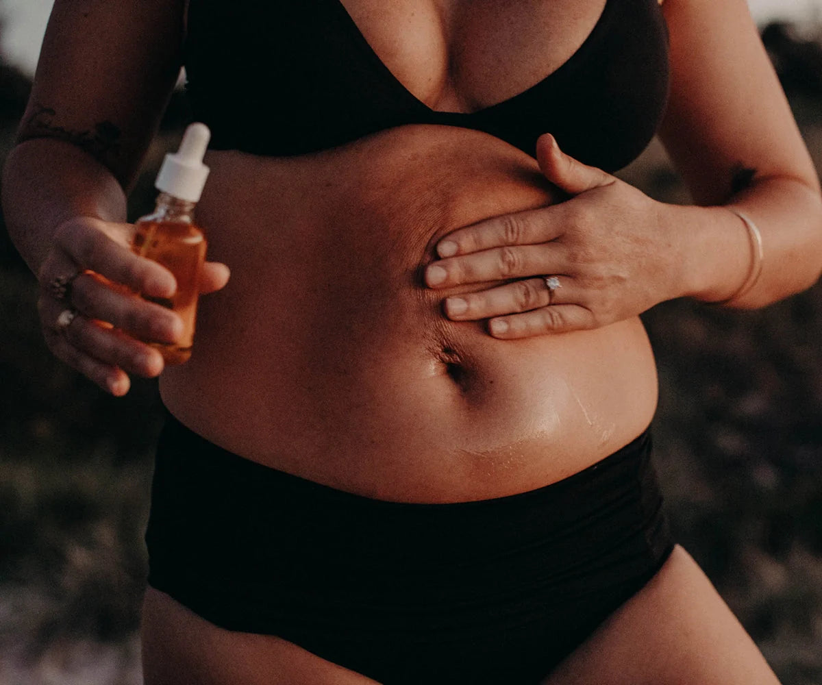 Woman applying Bare Mum Skin Scar Oil 50ml on stomach, suitable for use with baby strollers