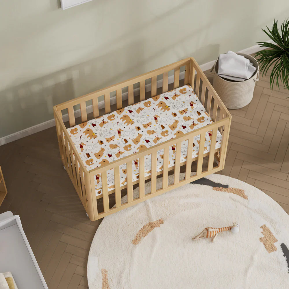Wooden baby crib with patterned sheet from Boori Turin Compact Cot with pocket spring mattress