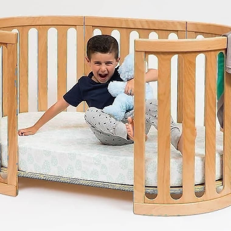 Wooden baby crib with child in Cocoon Nest Natural junior bed by Toshi Baby