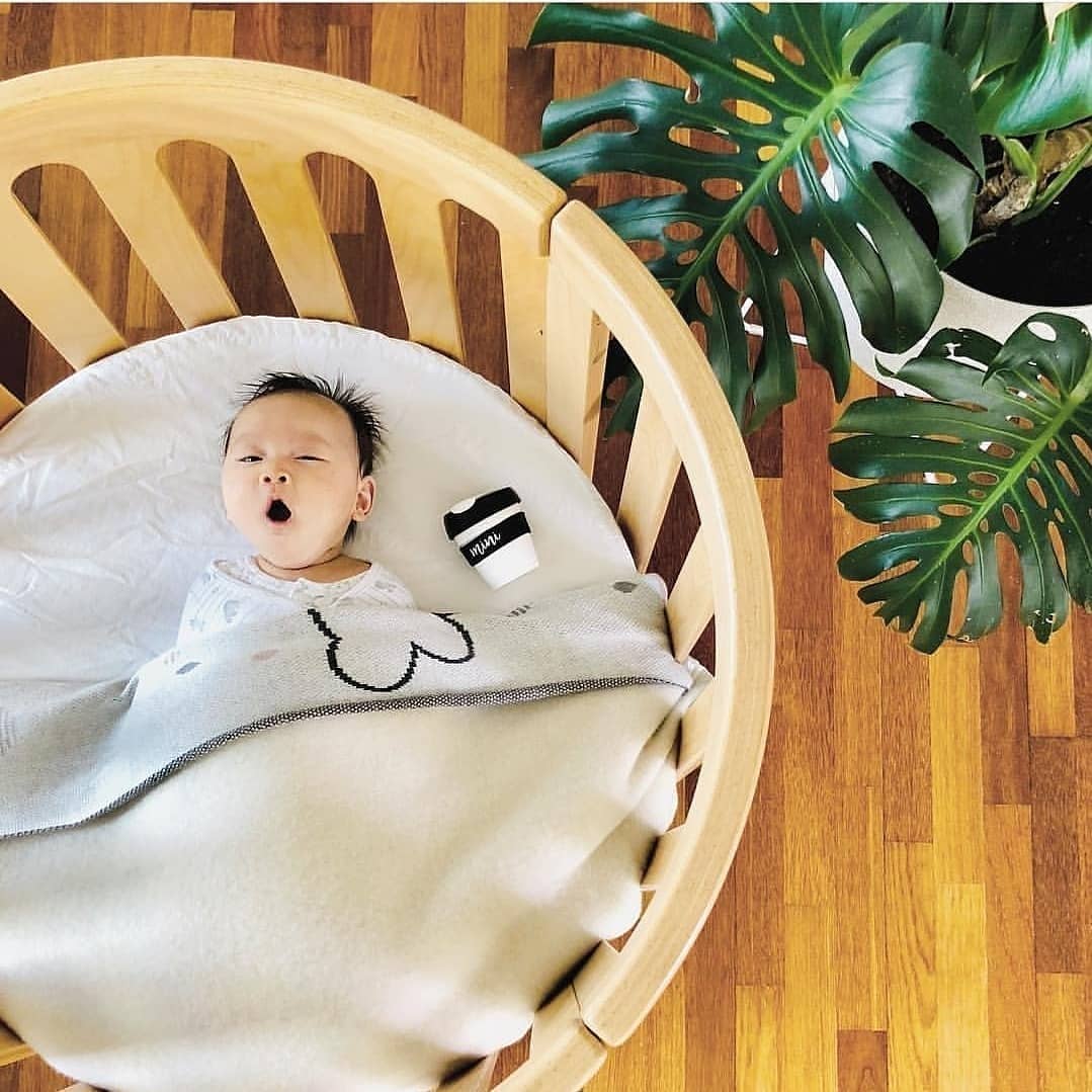 Baby in round wooden crib from Cocoon Nest Natural, perfect as a junior bed