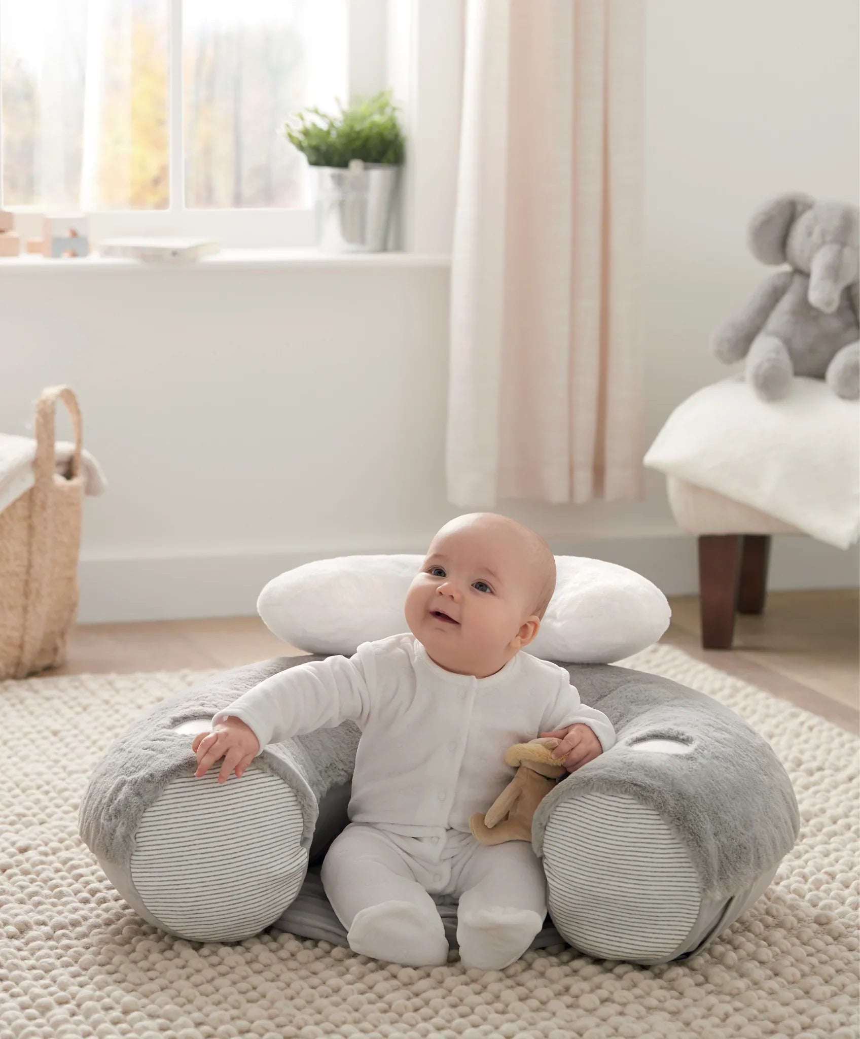 Cute baby in a gray plush support seat from MaMas & Papas Sit & Play baby floor seat