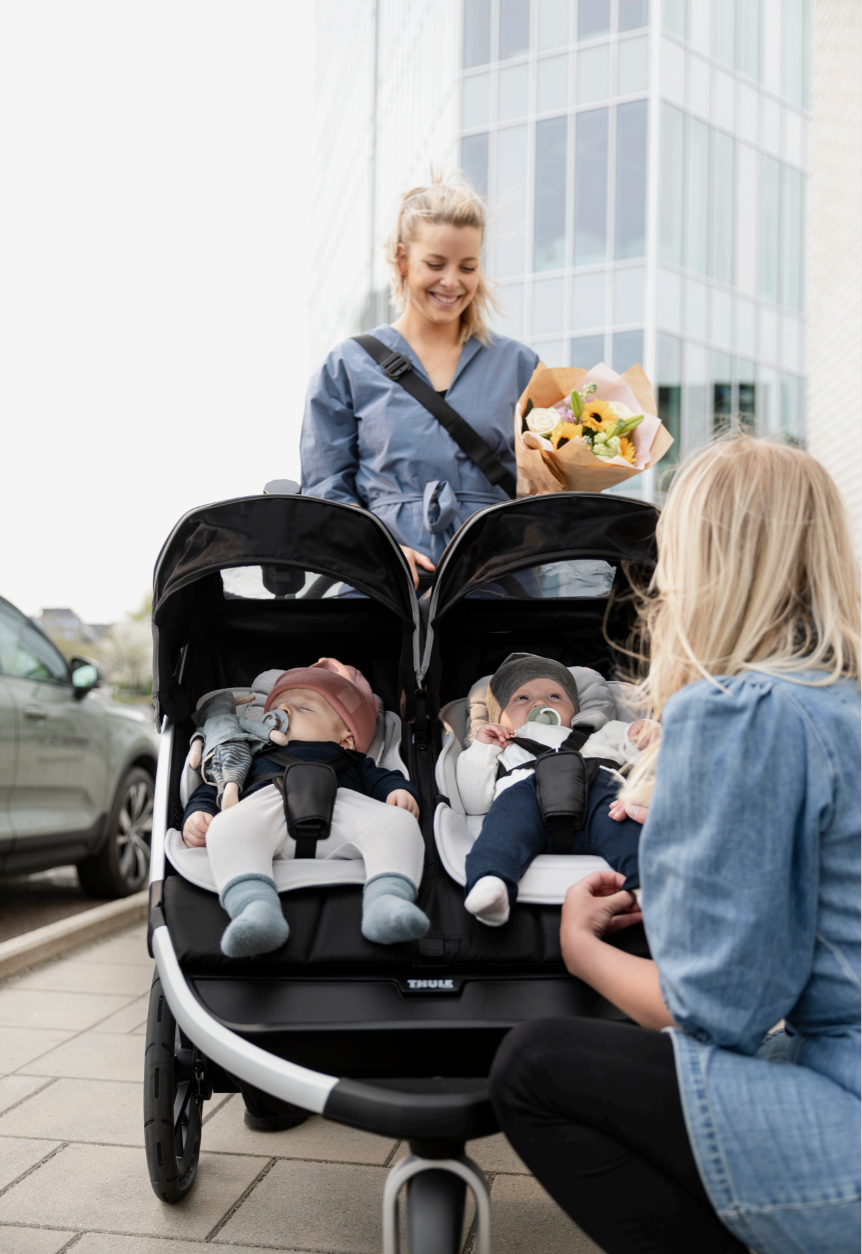 Double stroller with two babies wearing toshi baby rompers, featuring Thule Newborn Inlay