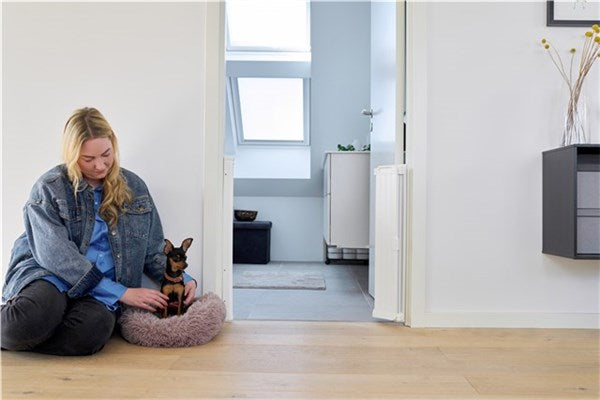 Woman petting small dog in fluffy bed near DogSpace Marley Retractable Guard doorway