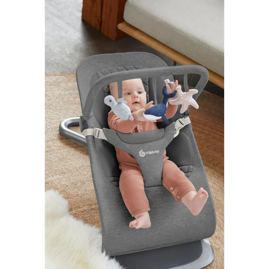 Gray baby bouncer with hanging toys from Ergobaby Evolve Ocean Wonders ultimate bouncer toy