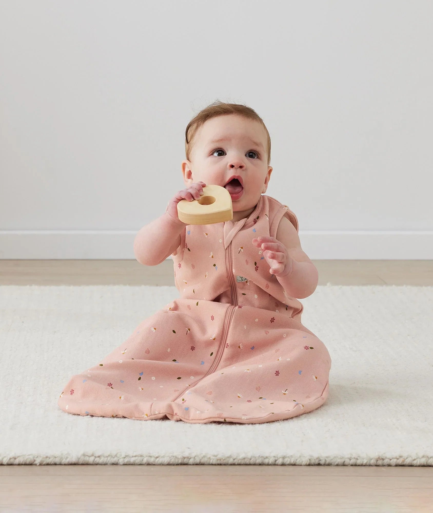 Baby in pink ergopouch jersey sleeping bag with daisies print for cozy sleep