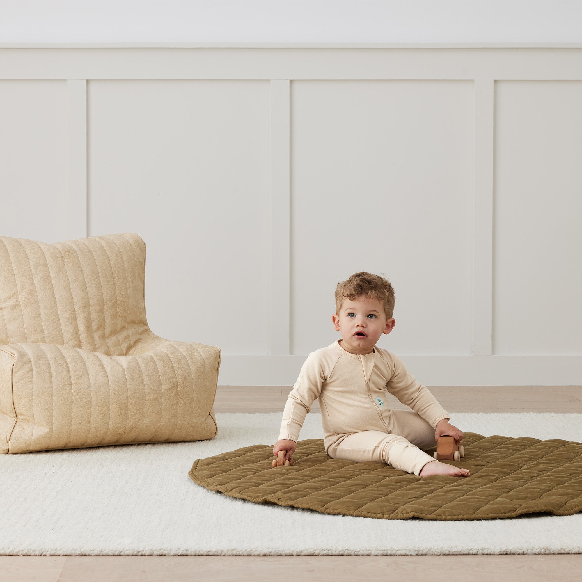 Baby in Ergopouch Long Sleeve Layer 1.0 TOG Vanilla on quilted playmat in organic jersey cotton