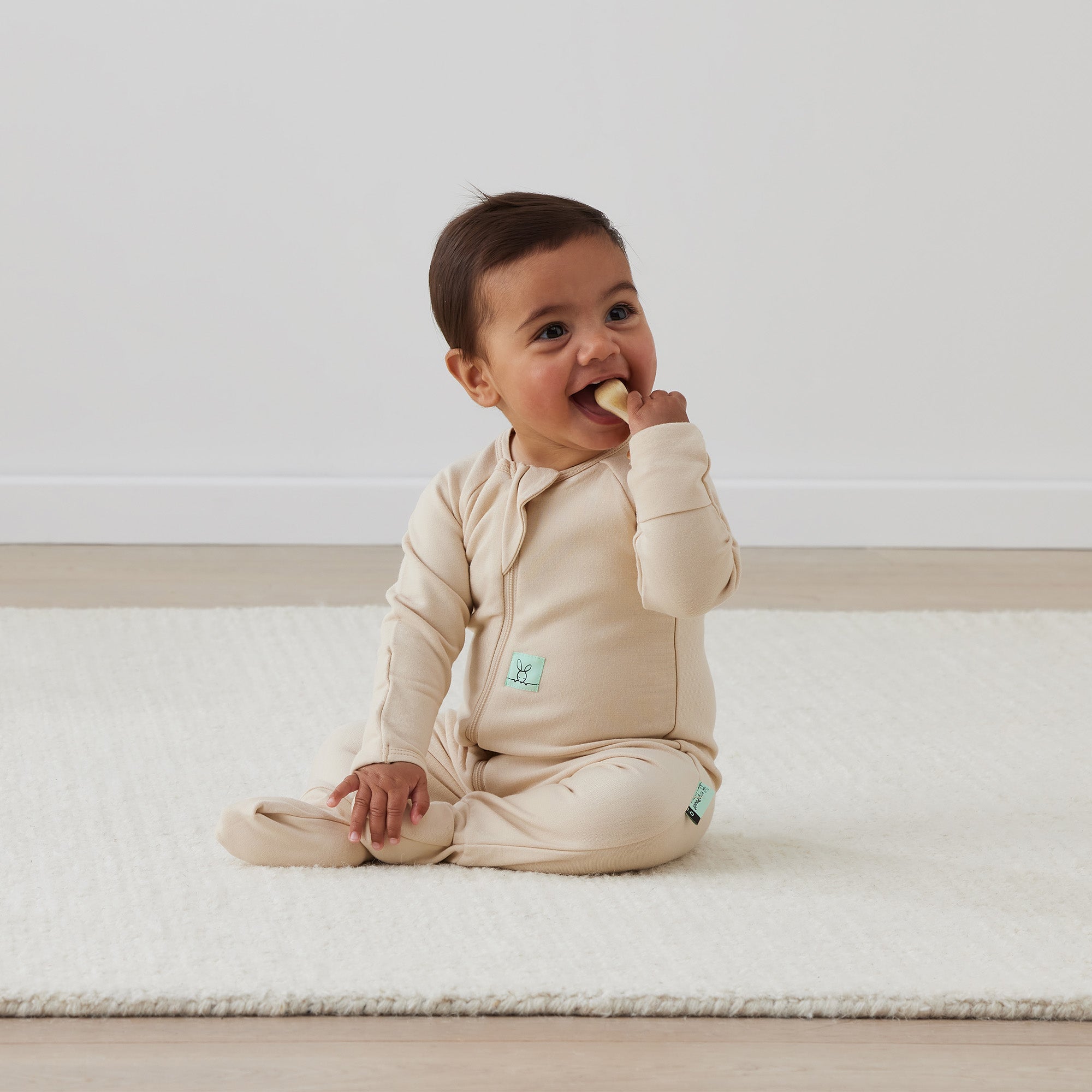 Baby in beige ergopouch long sleeve pajamas made from GOTS certified organic jersey cotton