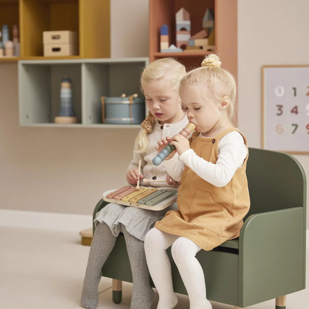 Two young girls playing musical instruments with Flexa Flute and Clapper toy setup