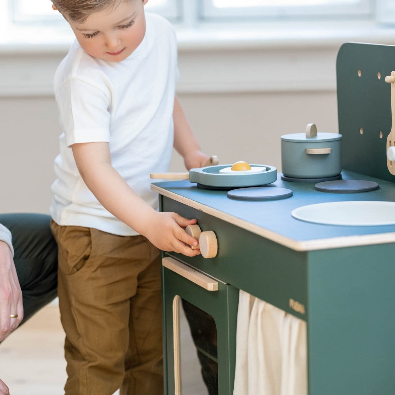 Green and wood toy kitchen on the Flexa Kitchen with toshi baby romper and Odyssey wagon wheels