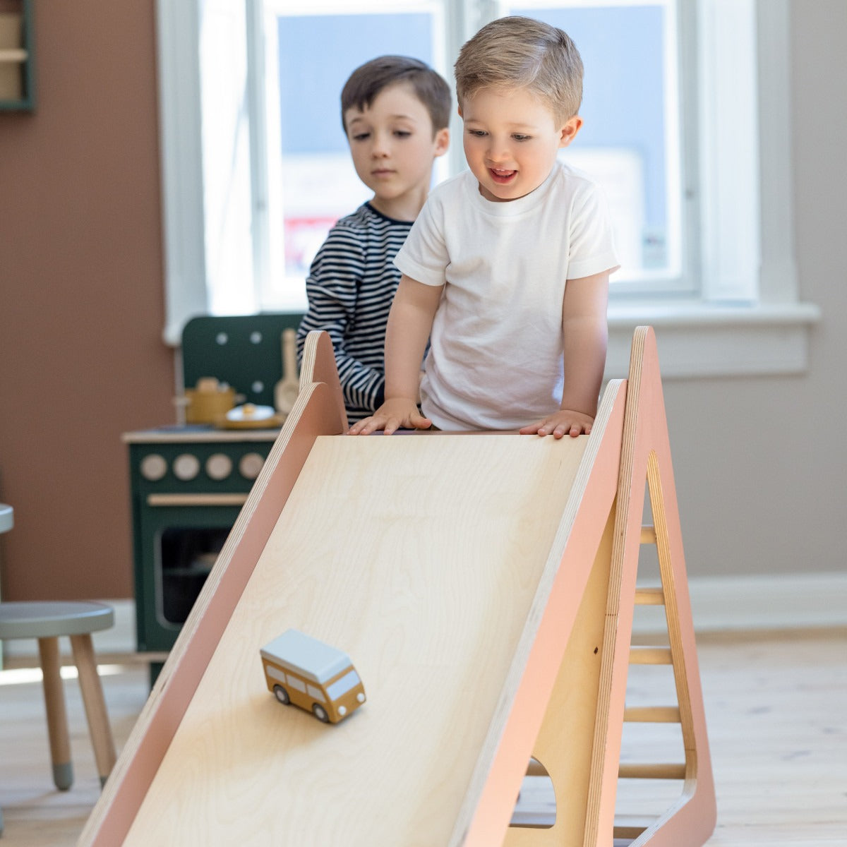 Kids playing on a wooden Flexa Play Tower with Slide featuring Toshi Baby Romper and Odyssey Wagon Wheels