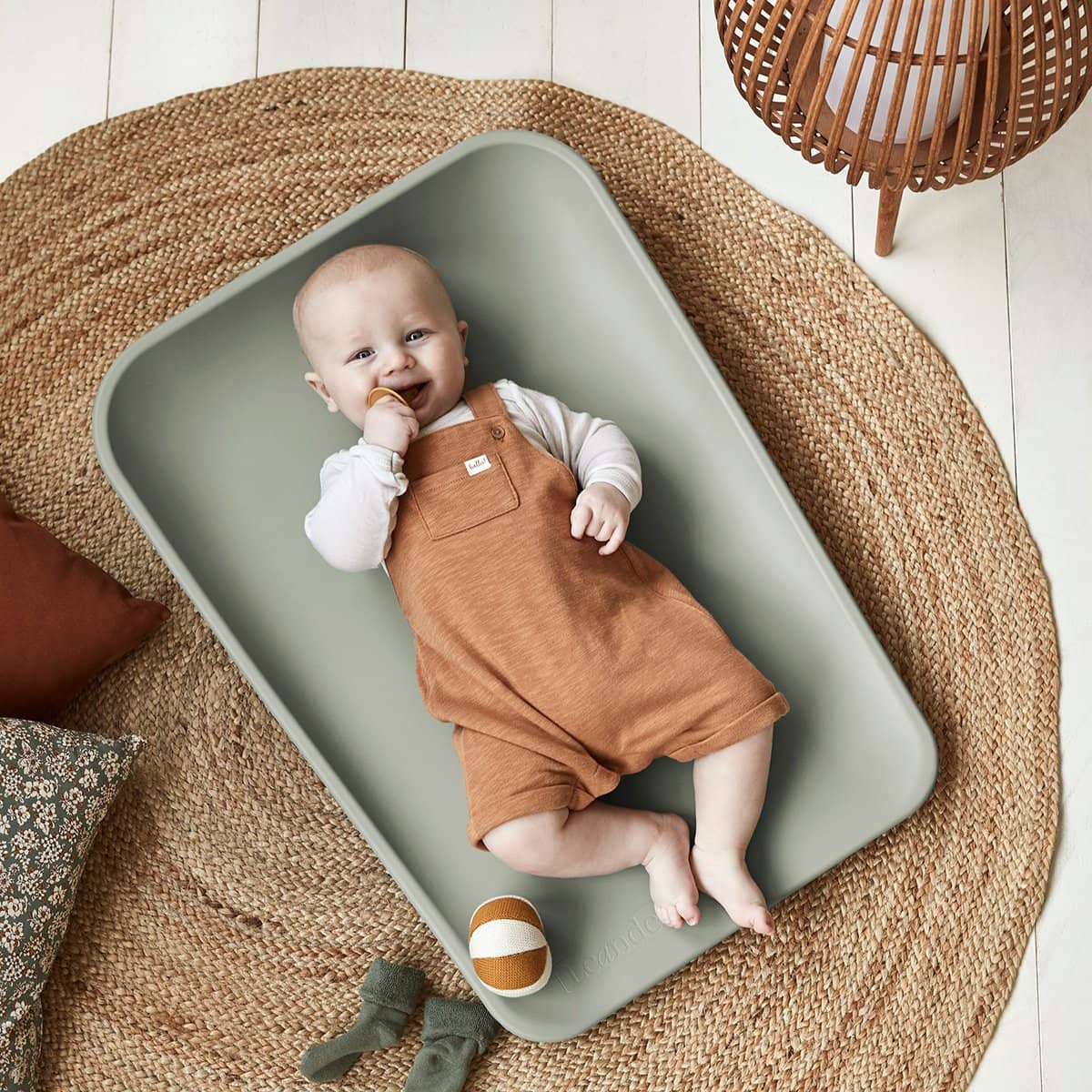 Baby in a sage green Toshi Baby Leander Matty Change Mat for easy diaper changes