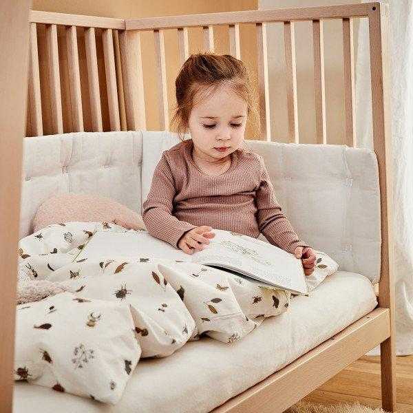 Child reading in a toshi baby Linea Cot Natural 120cm x 60cm