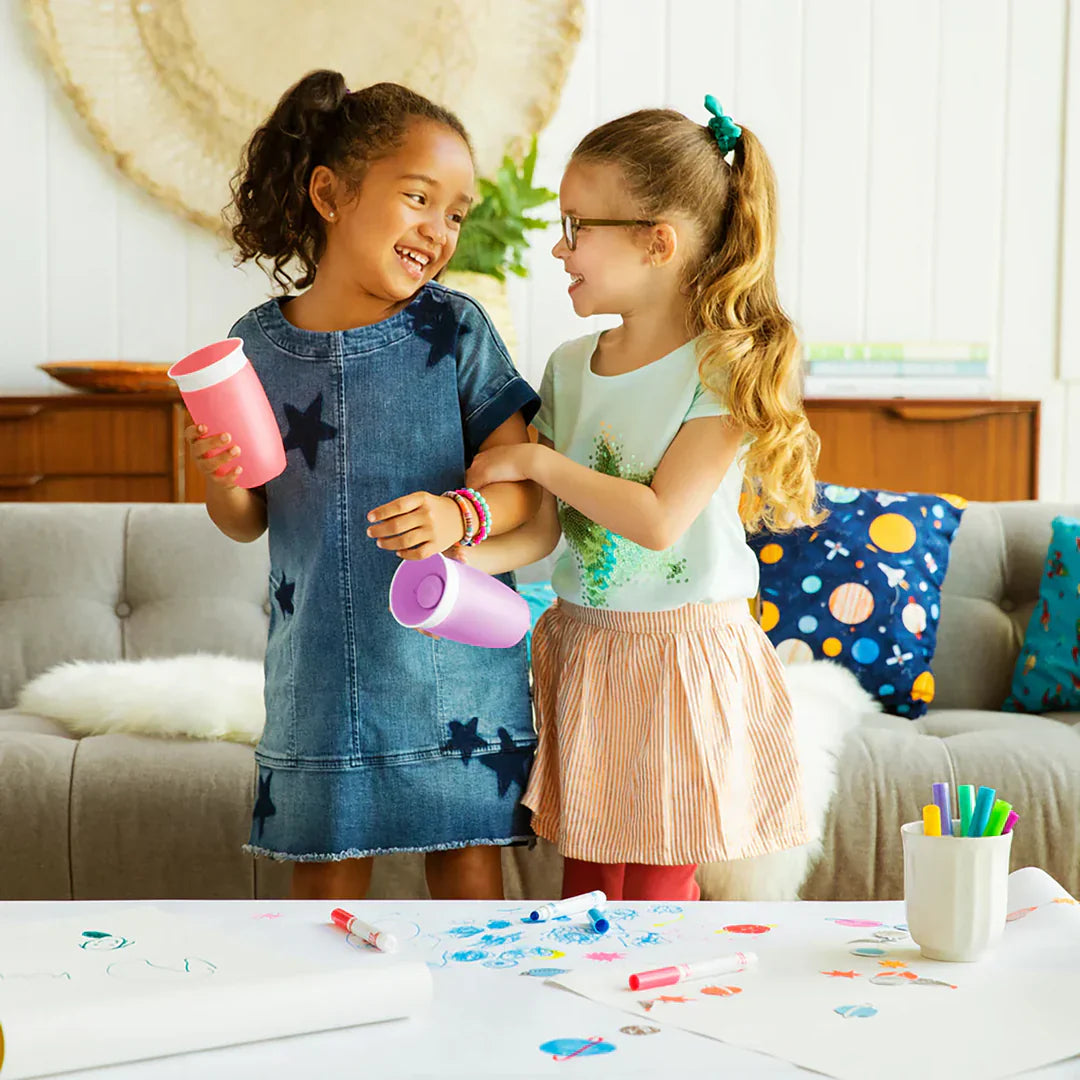 Two young girls holding pink cups with miracle 360° cup design on Odyssey wagon wheels