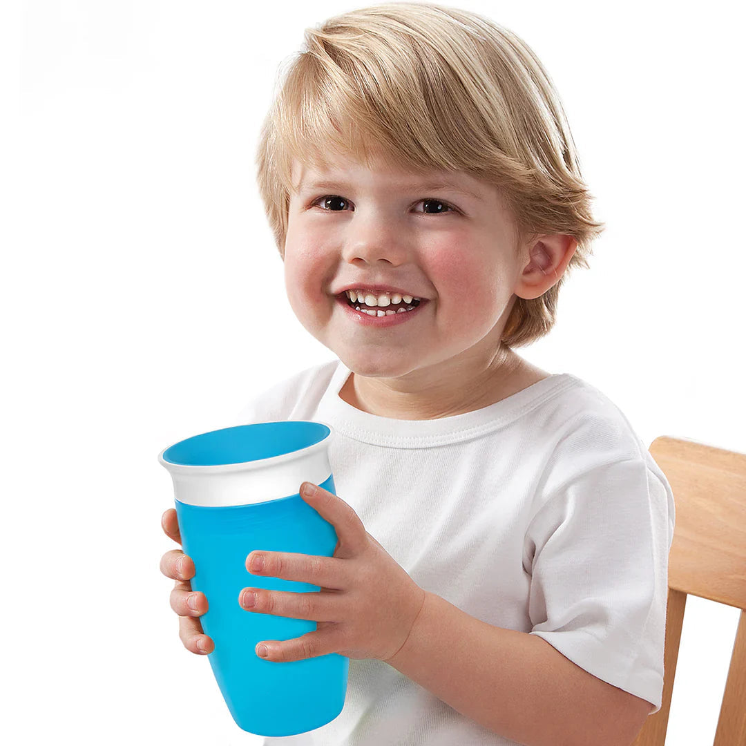 Smiling kid with a blue miracle® 360° Sippy Cup, perfect for baby strollers or on the go