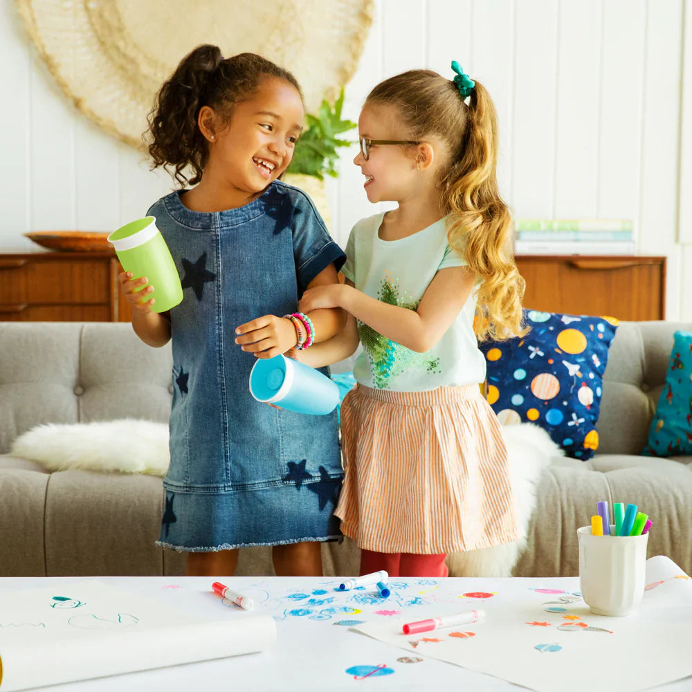 Two young girls holding cups with Munchkin 10oz Miracle and Toshi Baby Romper