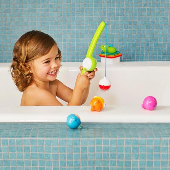 Smiling kid playing with Munchkin Fishin Bath Toy in bathtub, perfect for Toshi Baby fun