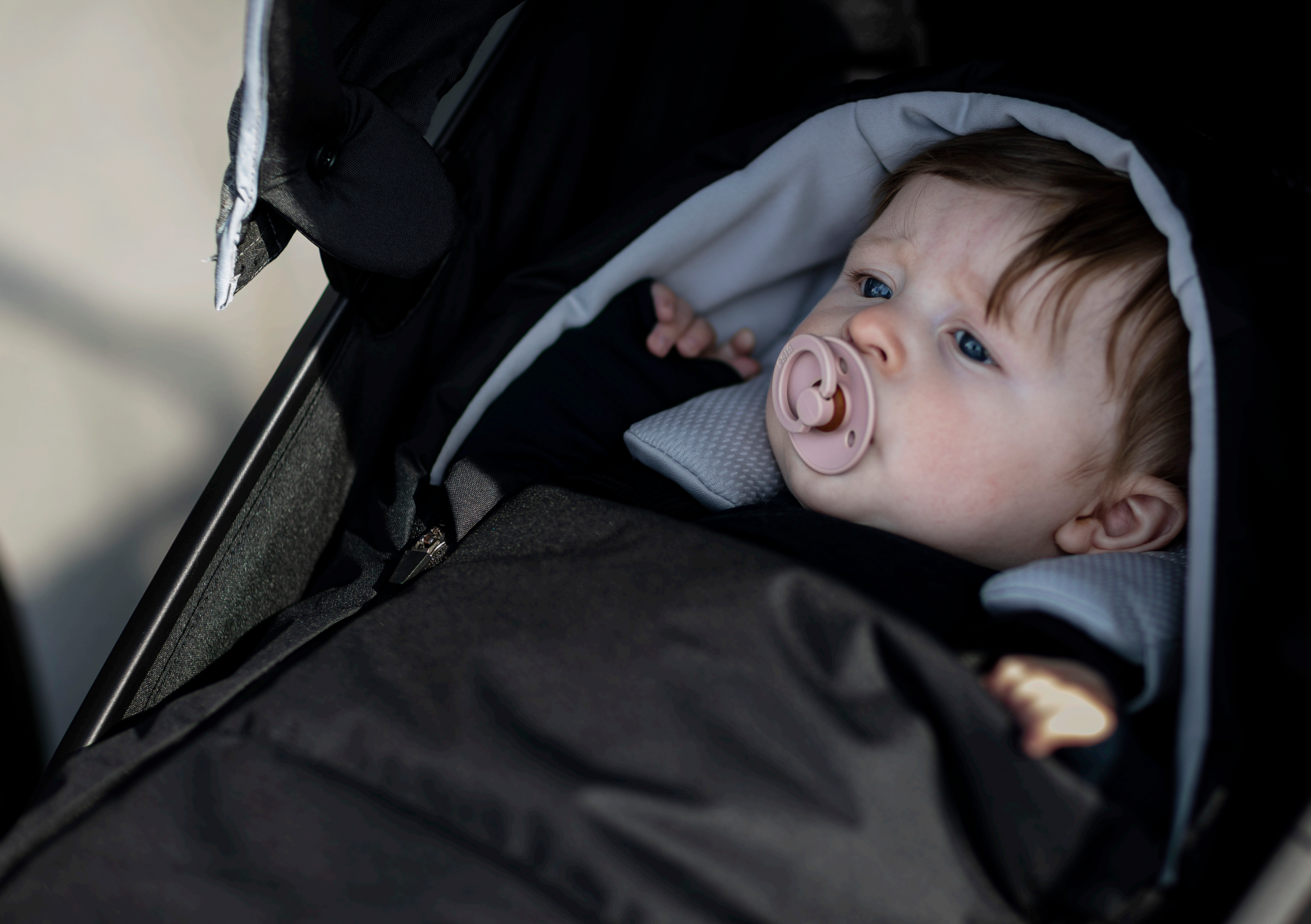 Baby in stroller with pacifier in Thule Newborn Nest, perfect for Toshi Baby Romper and Odyssey Wagon Wheels