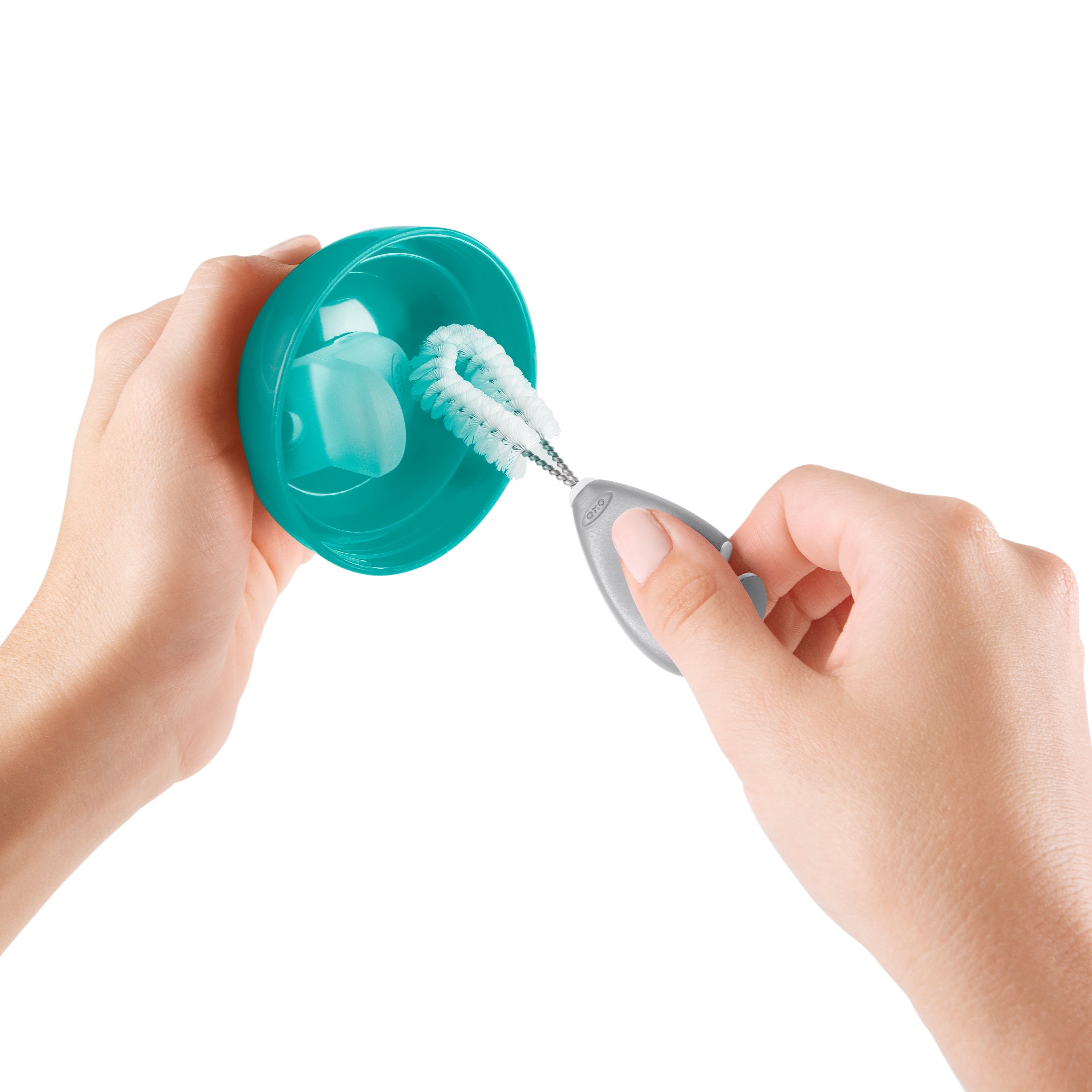Teal cup being cleaned with a brush from Oxo Tot Bottle & Cup Cleaning Set grey