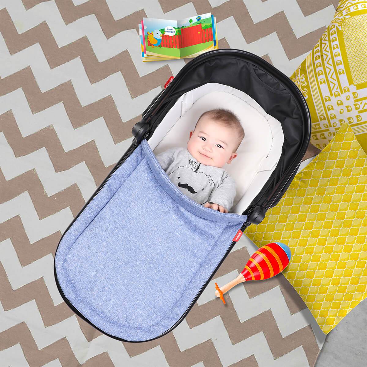 Baby in a blue Phil&Teds Snug Carrycot with toys on Odyssey Wagon Wheels stroller