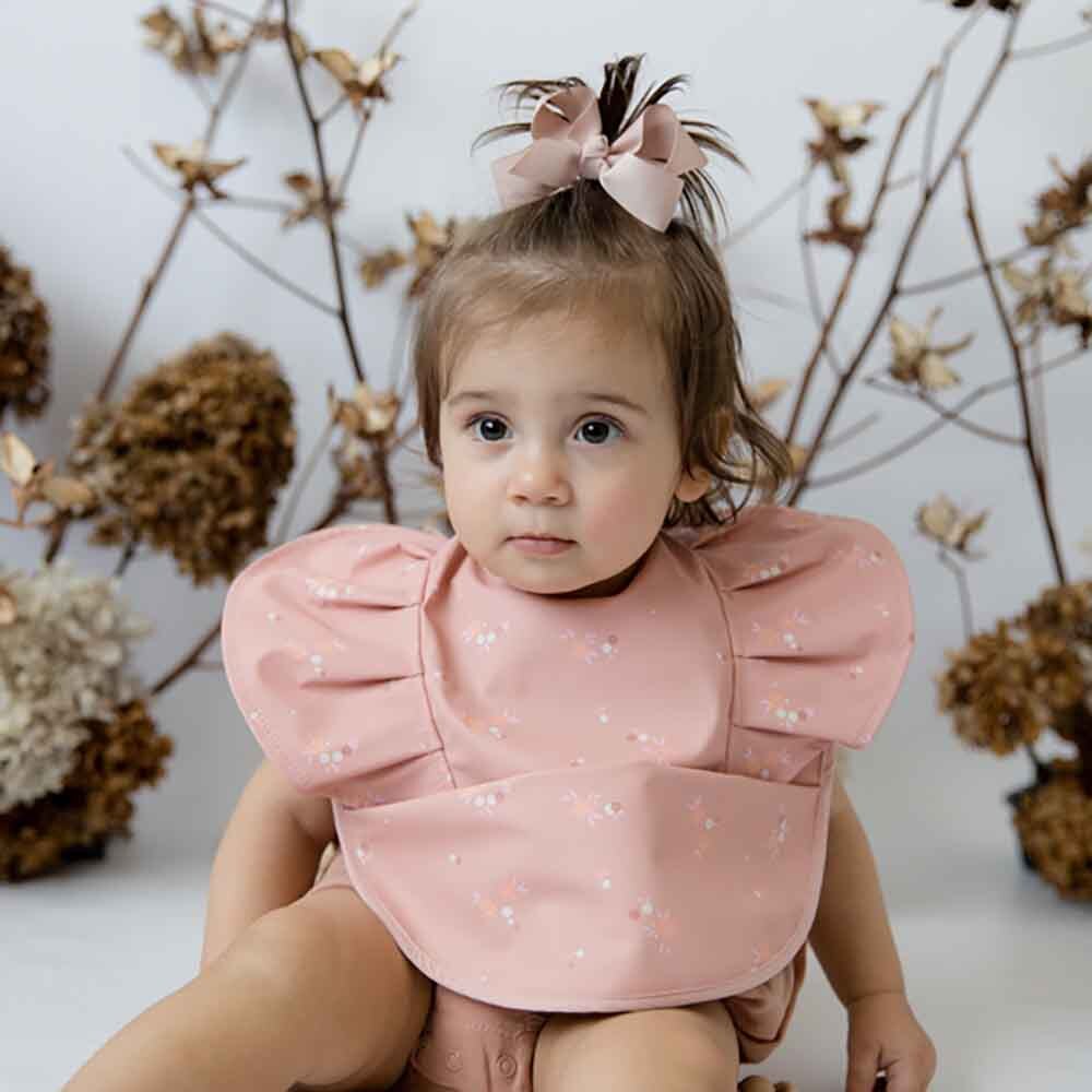 Baby in pink ruffled bib from Snuggle Hunny Toshi Baby, perfect for baby strollers