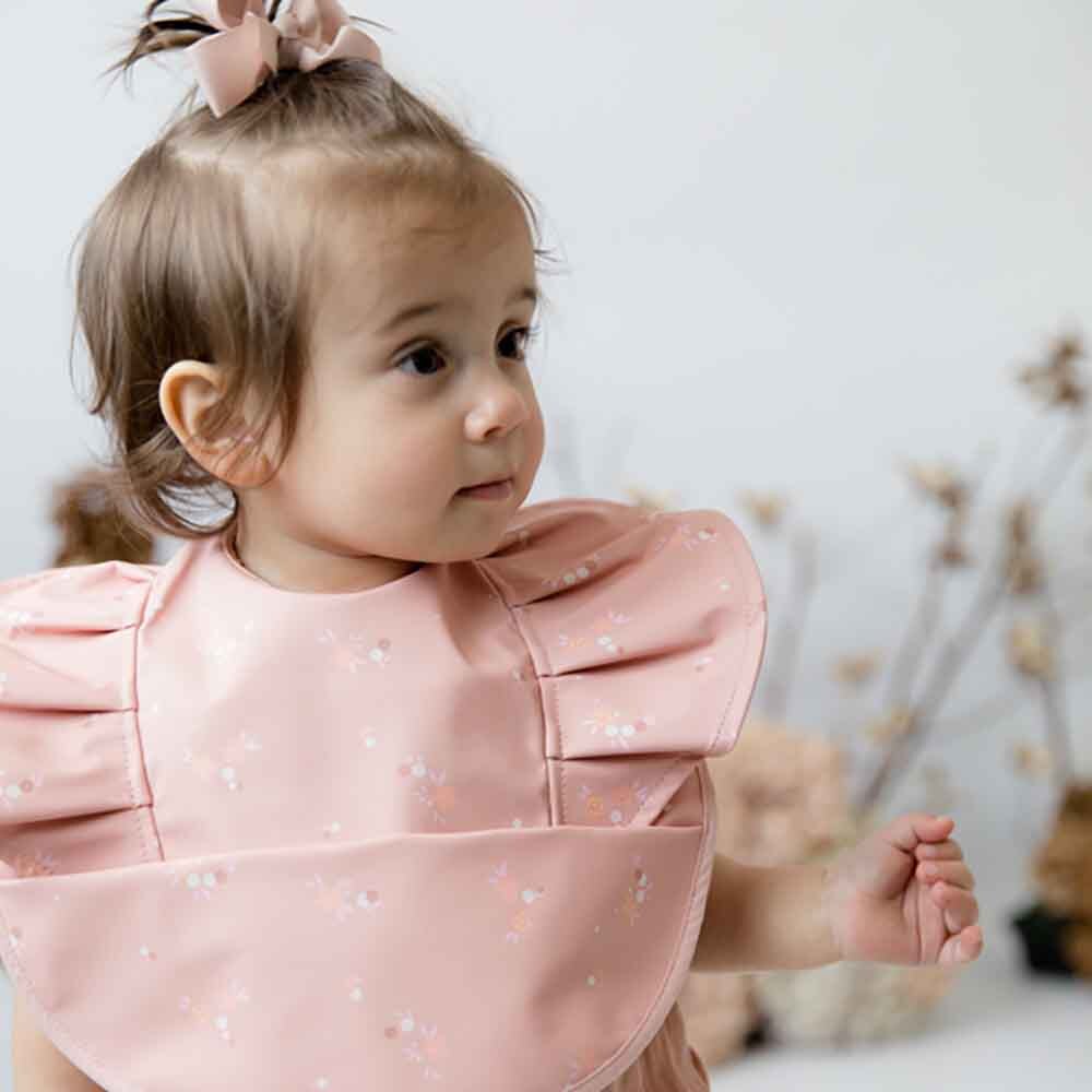 Baby wearing a pink ruffled bib from Snuggle Hunny Toshi Baby collection