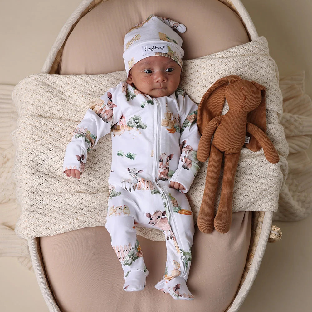 Baby in patterned Snuggle Hunny Farm Organic Snuggle Sleepsuit with bunny doll