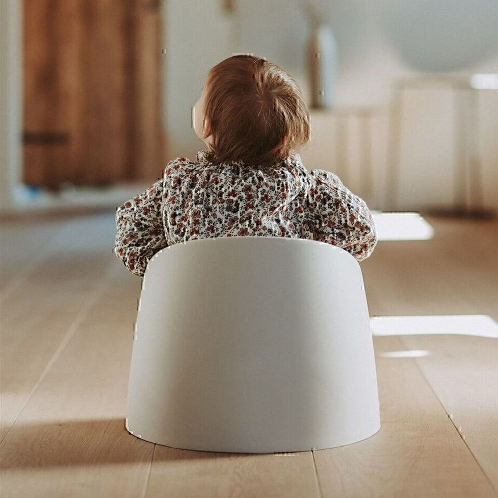 Child sitting in a white chair on Quax My Potty Clay with Toshi Baby Romper and Odyssey Wagon Wheels