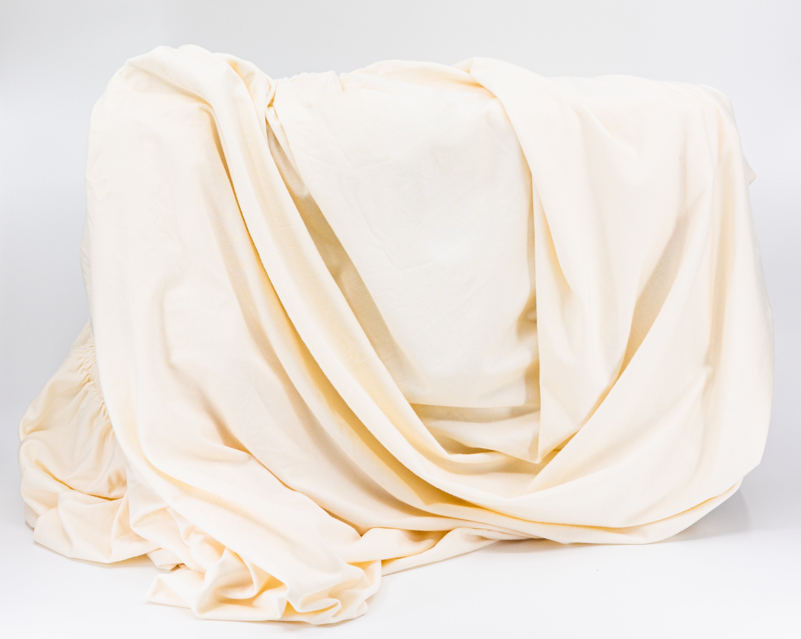 Draped cream-colored fabric for Tasman Eco Fitted sheets, perfect for bare mum postpartum style