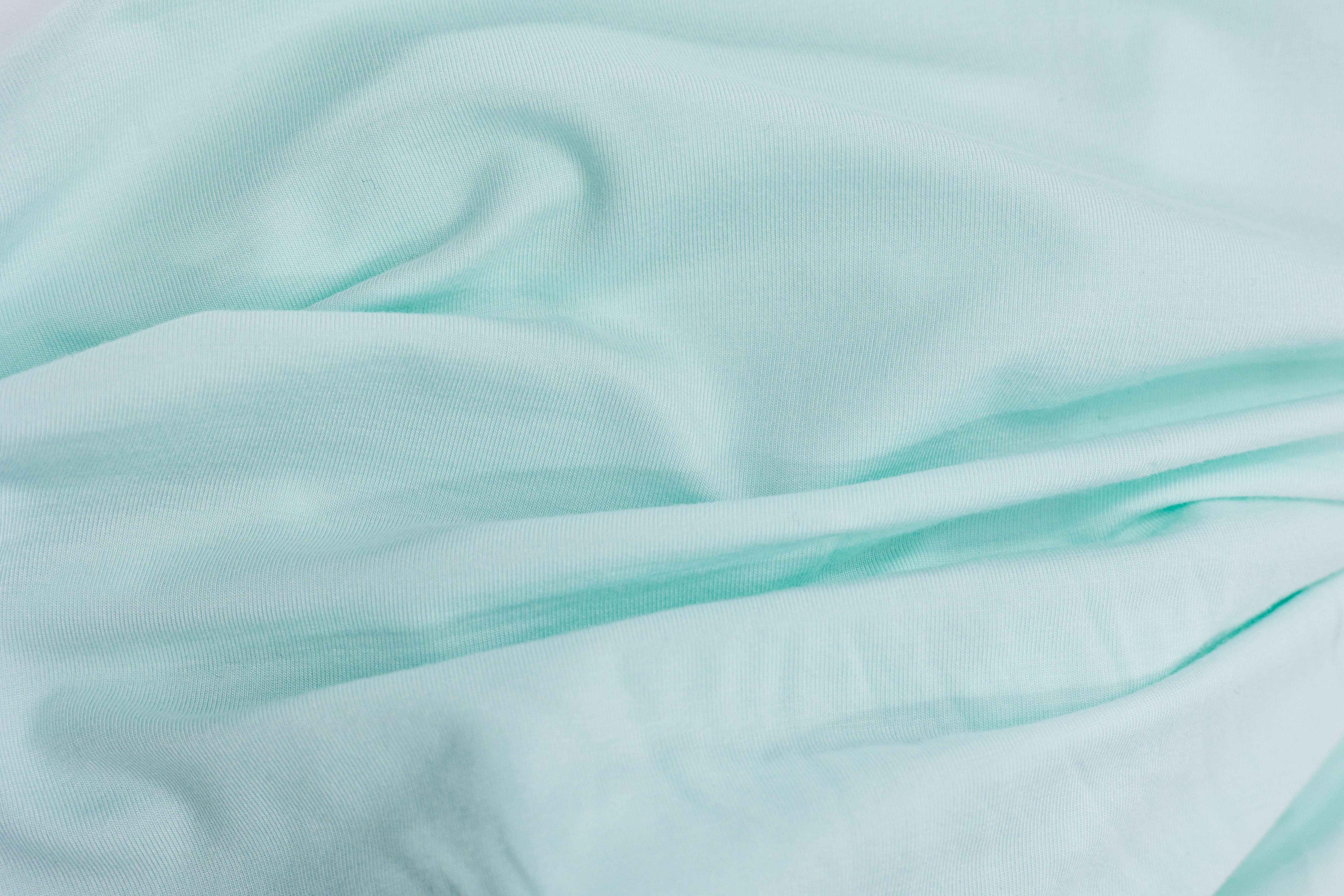 Wrinkled light blue Tasman Eco Fitted sheet for comfy baby and mama moments
