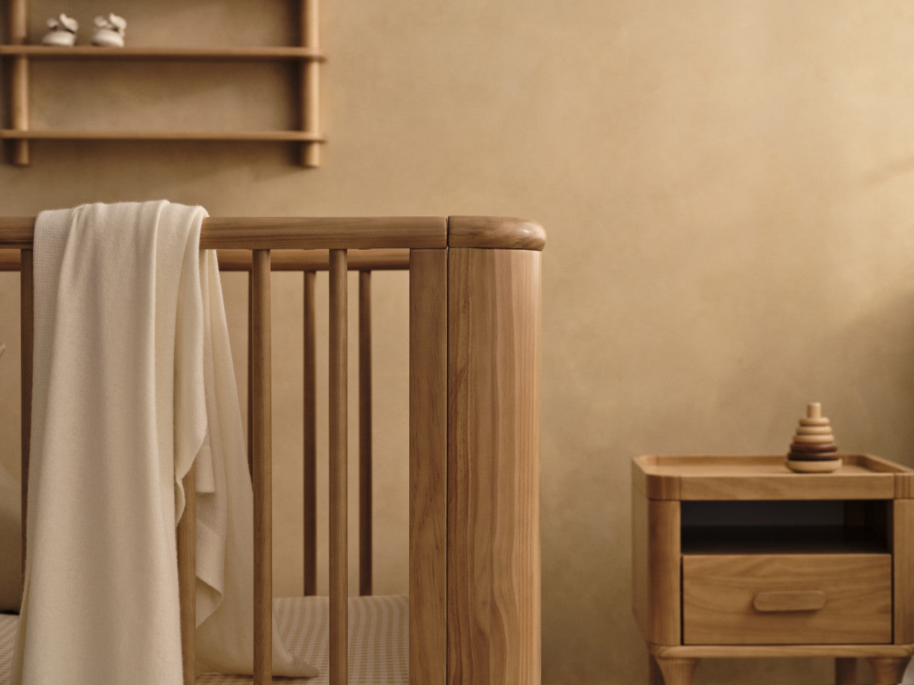 Wooden baby crib with blanket from Tasman Eco Willow Cot, perfect for nursery and baby strollers