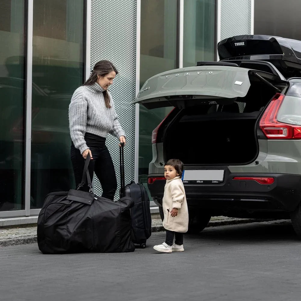 Woman with luggage near car using Thule Stroller Travel Bag for Toshi Baby stroller