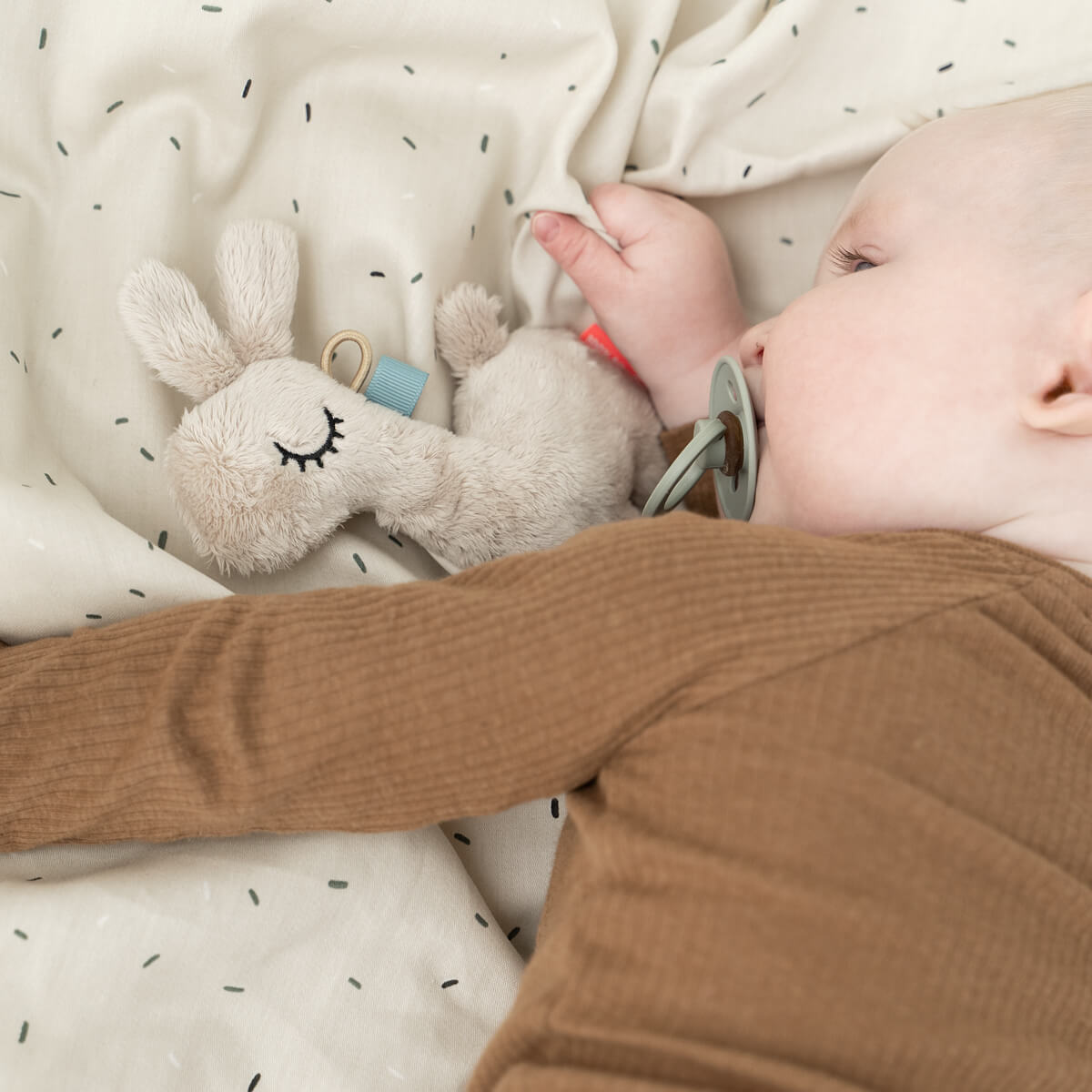 Baby sleeping with plush llama and Tiny Sensory Rattle, perfect for toshi baby romper