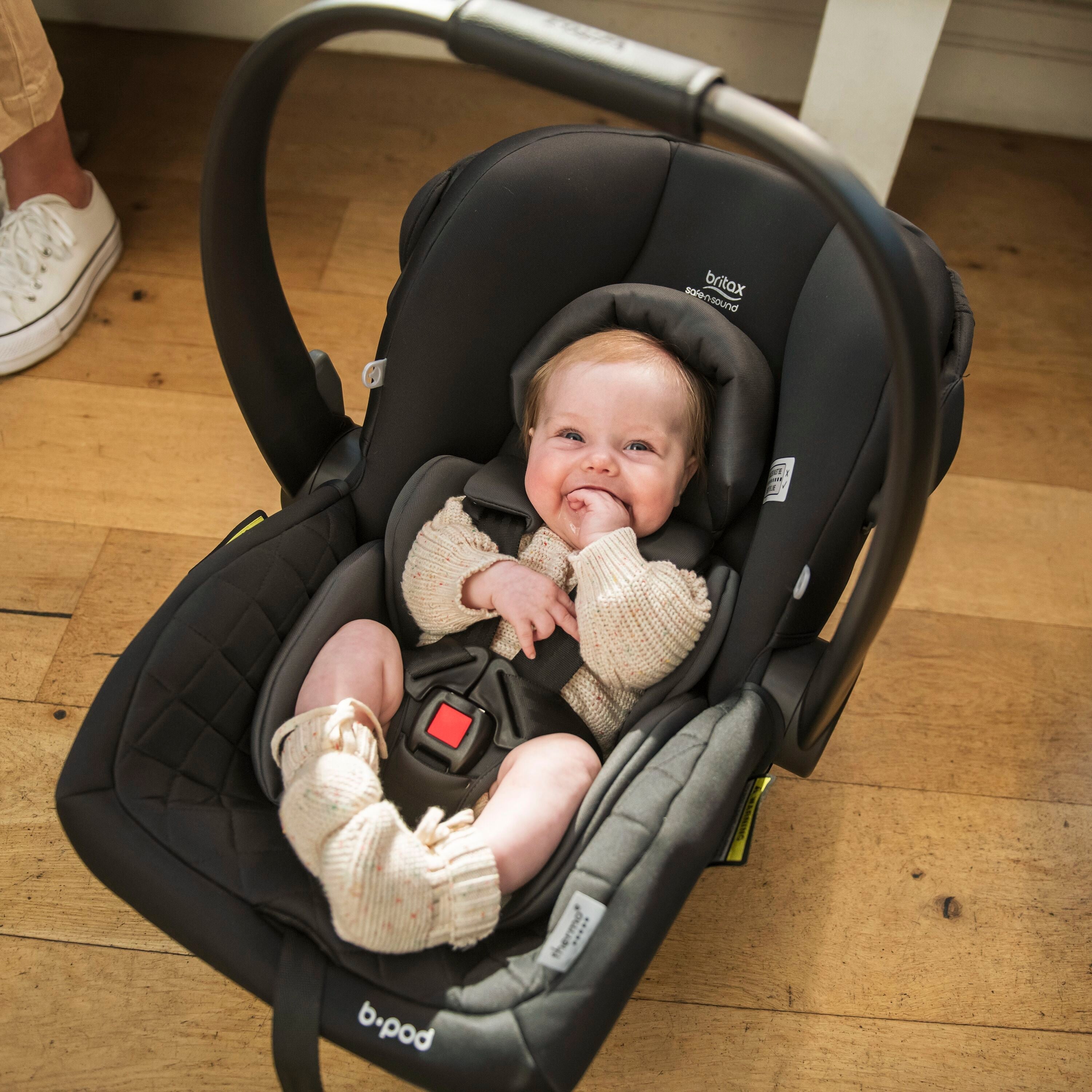 Black infant car seat with baby in Britax Safe-n-Sound b-pod capsule for safe travel