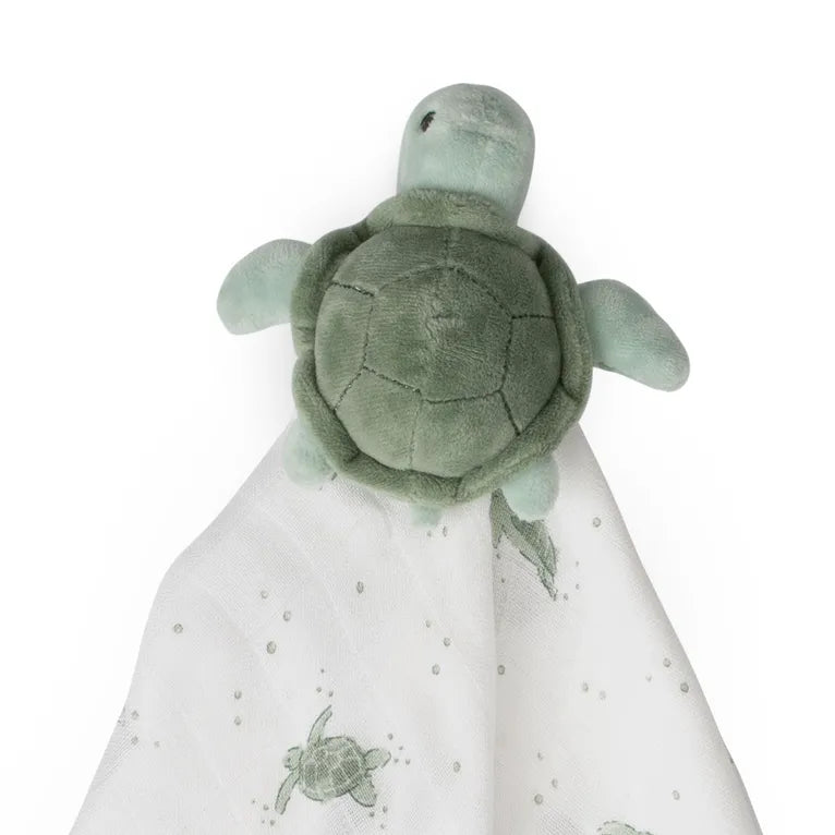 Plush turtle toy on a white blanket with turtle pattern