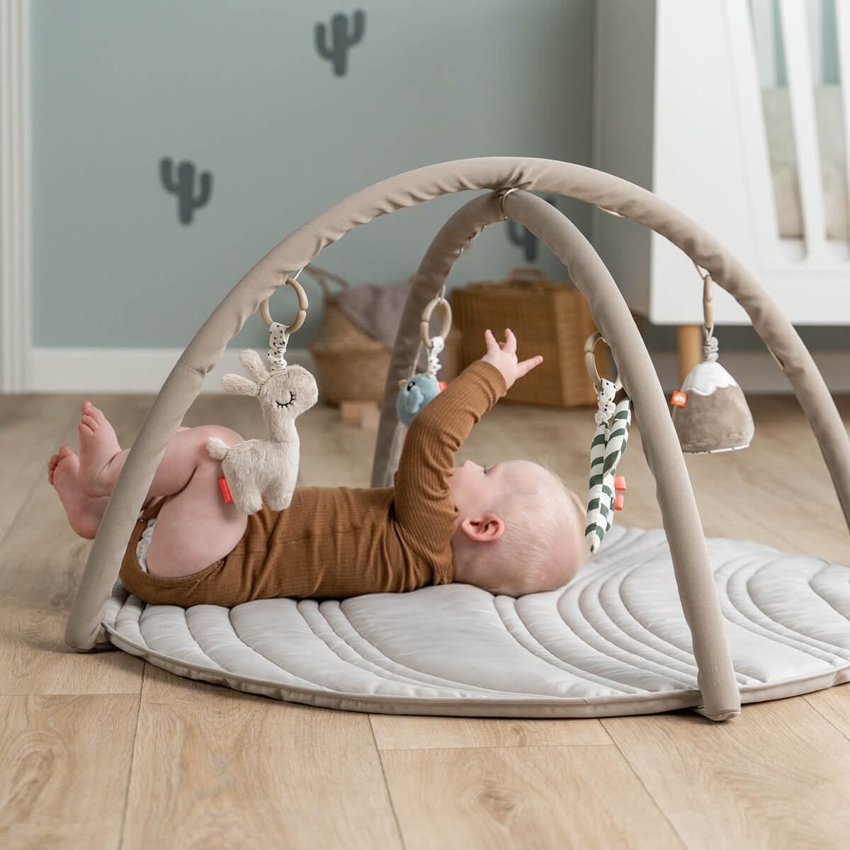 Baby activity gym with hanging toys on Done by Deer Activity Play Mat Sand, perfect for tummy time